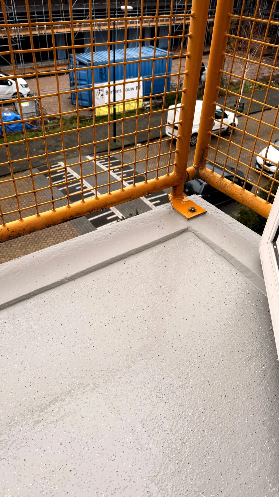 Afgewerkte balkonvloer met gele veiligheidshekken