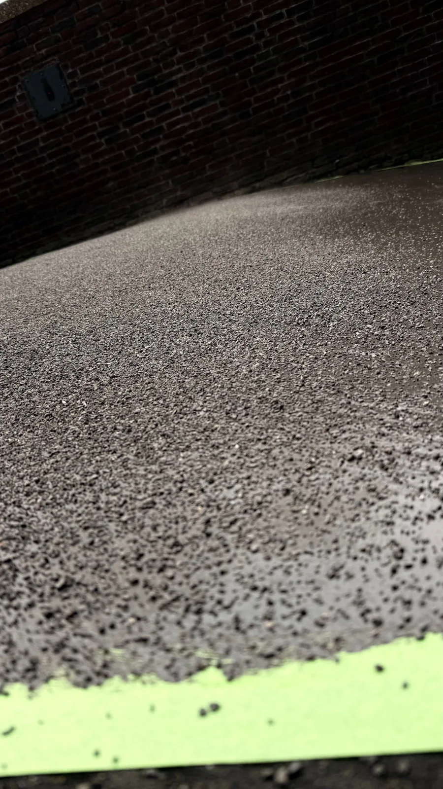 Detail van een donkere ingestrooide coating langs een afgeplakte rand