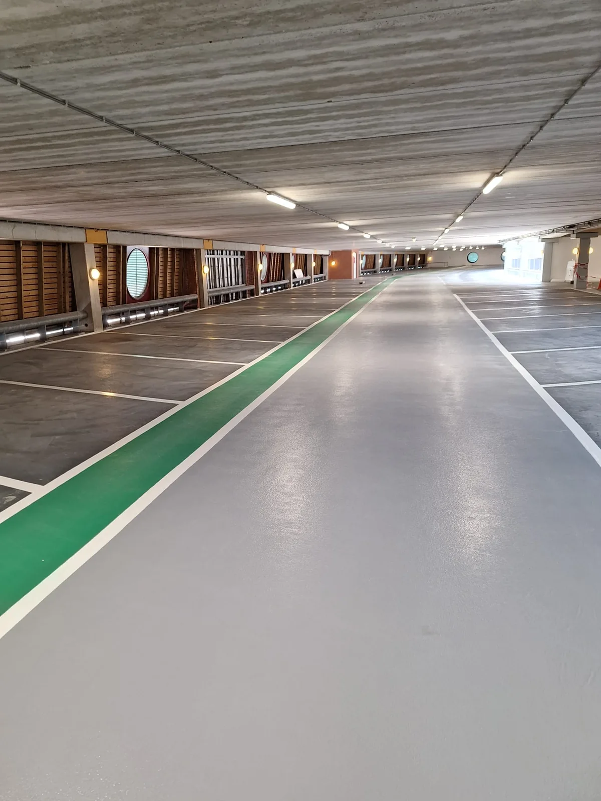 Overzicht van de parkeervloer met een groene loopstrook tussen de gemarkeerde parkeervakken