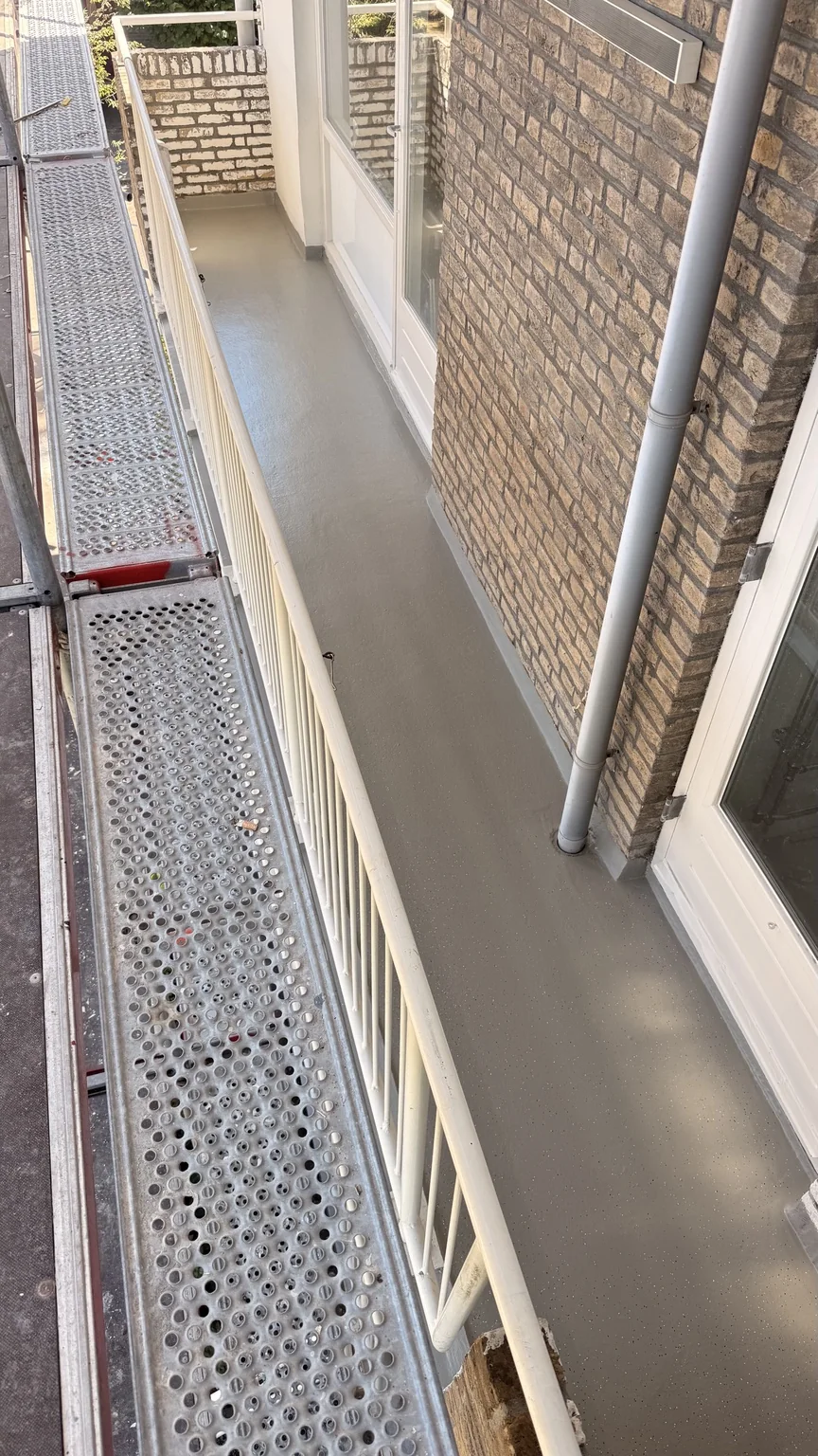 Gerenoveerde balkonvloer met Soprema ALSAN langs een bakstenen gevel in Leidschendam
