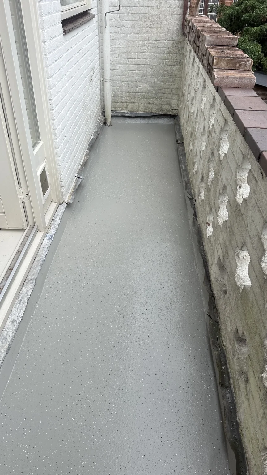 Gecoat balkon met witte gevel en gemetselde balustrade in Utrecht