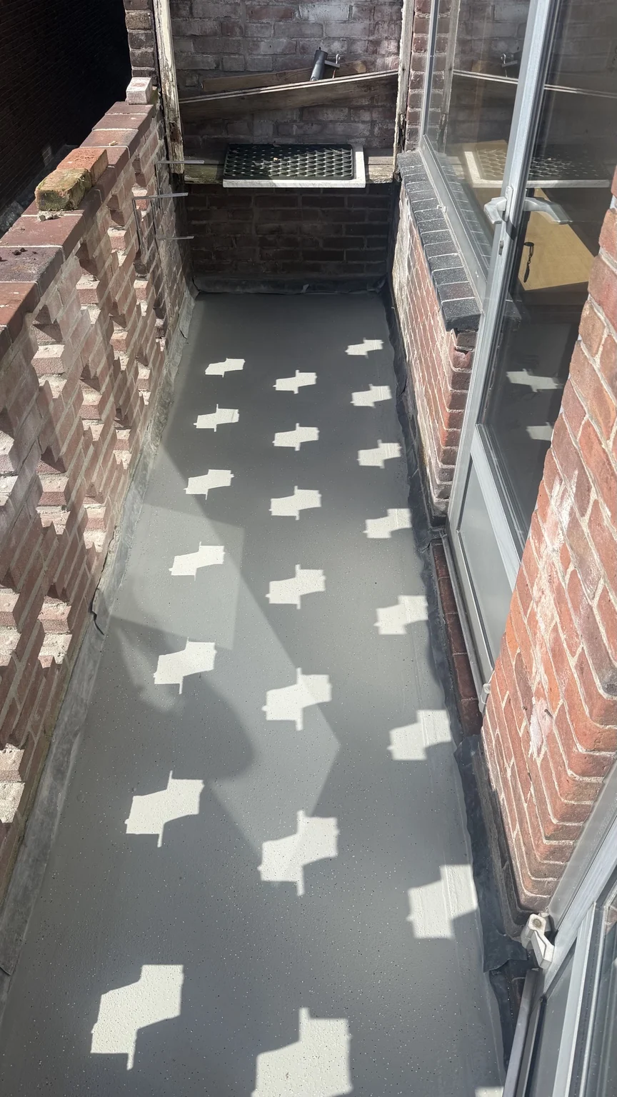Overzicht van een balkonvloer langs glazen deuren en een bakstenen balustrade